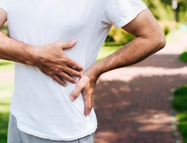 Hombre sujetándose la cadera por dolor durante una caminata