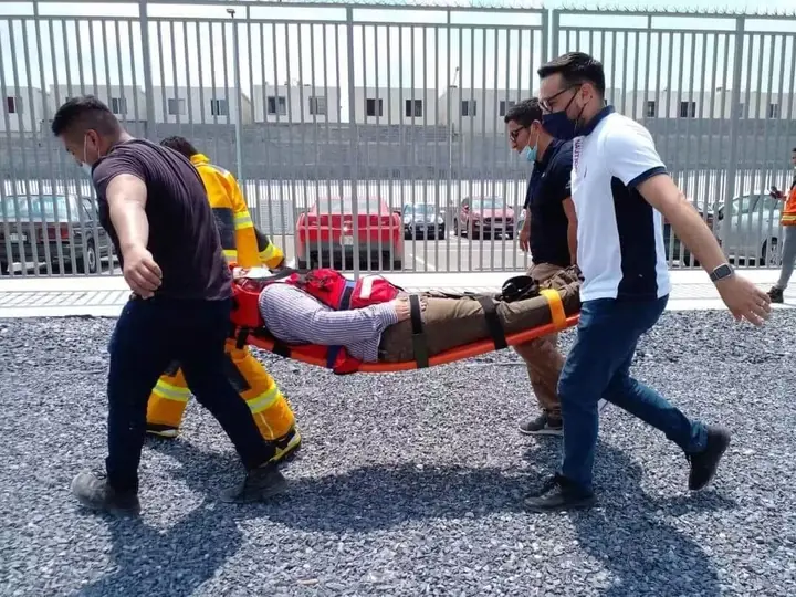 Brigadistas trasladando a un lesionado en camilla rígida