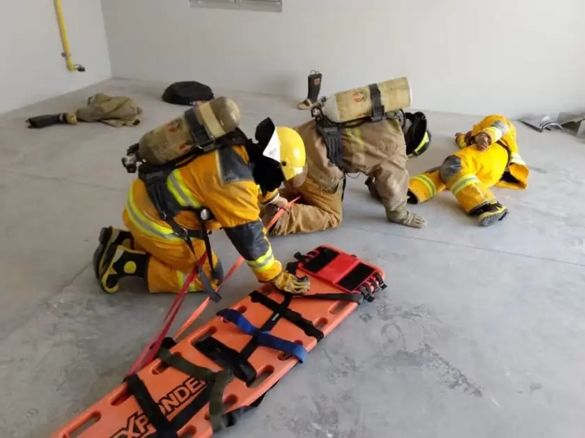 Brigada de emergencia practicando el traslado de un lesionado en camilla